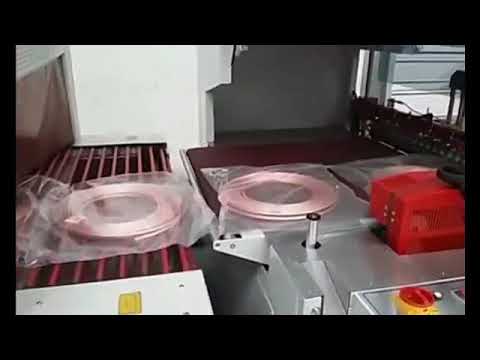Packaging and shrinking machine for copper tube coils optimized for efficiency and compactness. Packaging and shrinking machine for copper tube coils optimized for efficiency and compactness.